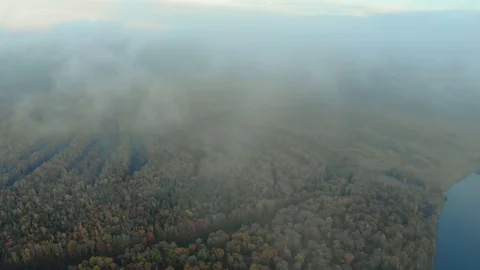Flying a drone over the clouds. View through the fog on the picturesque autumn Stock Footage 129539392