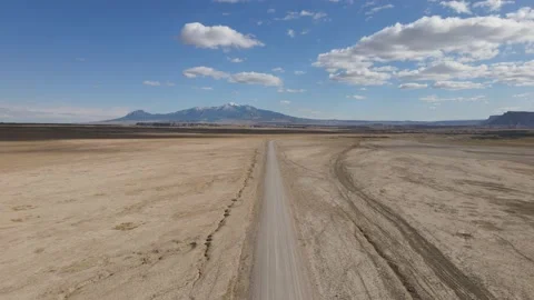 Flying drone over empty desert road with snow capped mountain in the distance Stock Footage 153872152