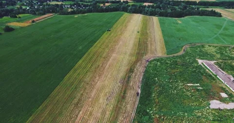 Flying on a Drone Over the Field Where the Tractor Works Stock Footage 64756099