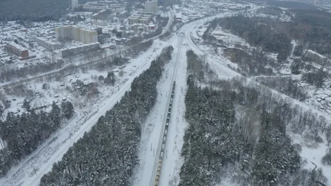 Flying on drone over a long train passing at a suburban station, winter forest Stock Footage 126361927