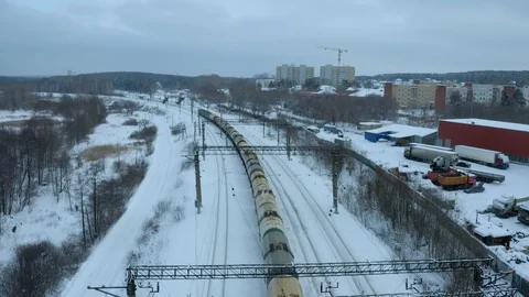 Flying on drone over a long train passing at a suburban station, winter forest Stock Footage 126362332