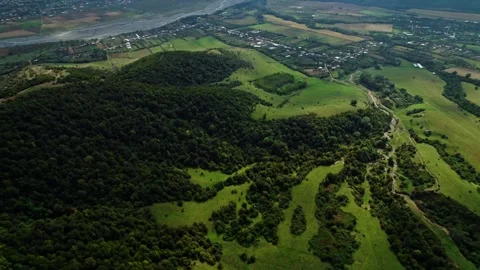 Flying a drone over a lush forest and village in Georgia on a cloudy day. Camera Stock Footage 275072415