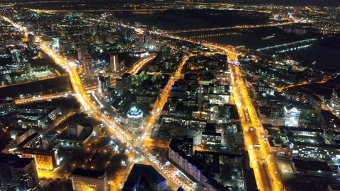 Flying drone over night city in yellow lights of light near river and bridge Stock Footage