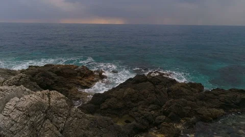 The flying drone over the waves with sea white foam crashing into rocky shore of Stock Footage 86725503