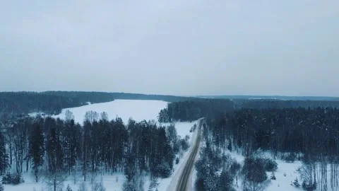 Flying a drone over a winter road and forest Video stock 169344532