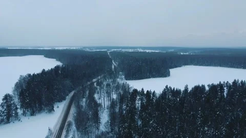 Flying a drone over a winter road and forest Video stock 169344549