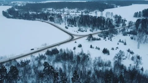Flying a drone over a winter road and forest Video stock 169344561