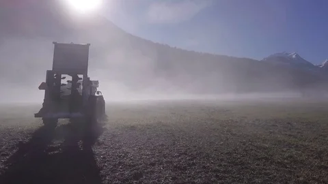 Flying a drone passing by a tractor in a field in France in a fog Stock Footage 86818229