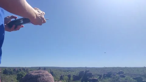 Flying a drone with a remote controller over a natural landscape. Stock Footage 312898004