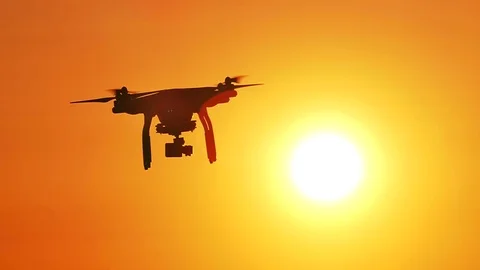 Flying drone  rotate in  front of  orange sky. Slow motion  Video stock 76485080