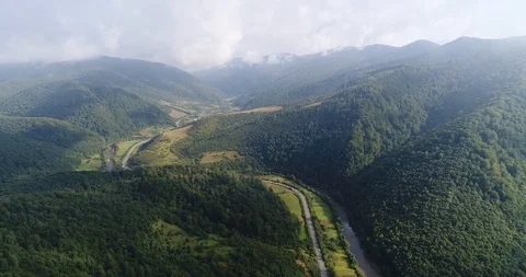 Flying drone through clouds over the green mountains valley covered with lush Stock Footage 85897776