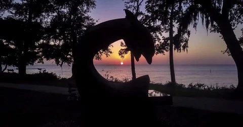 Flying a drone through a dolphin statue at sunset Stock Footage 81992739