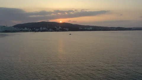 Flying by drone towards sunrie above mountaing and floating boat in the sea wate Stock Footage 124106923