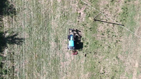 Flying drone tracking blue tractor mowing field before plowing and sowing Stock Footage 318823877