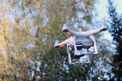 Flying drone. Trees on background. Space for text. Stock Photos