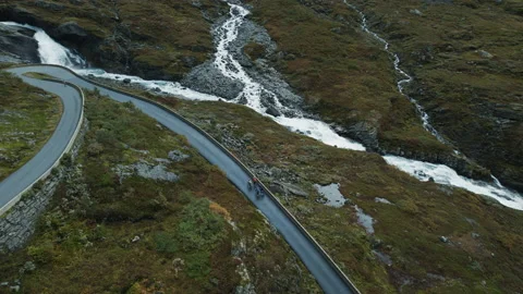 Flying drone view of cyclists riding up on road Stock Footage 188171792