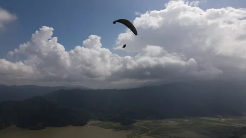 Flying a drone with a view of a flying paragliding pilot. Stock Footage 245127992