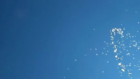 Flying drops and splashes of water on background of blue sky and bright sun Stock Footage 133639468