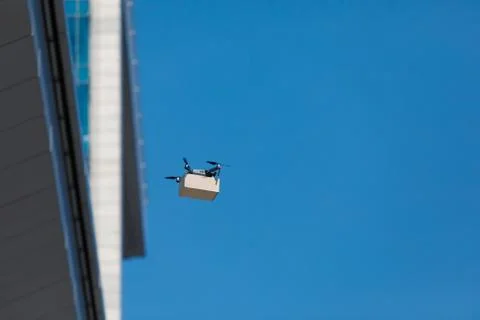 Flying electric drone with small parcel. Side view. Fotos de archivo