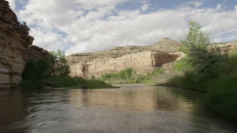 Flying fast and low over river panning up on red cliffs Stock Footage 141626235