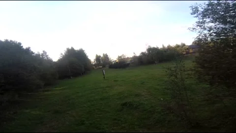 Flying on an fpv drone in a green field, against the background of a forest Stock Footage 166837077