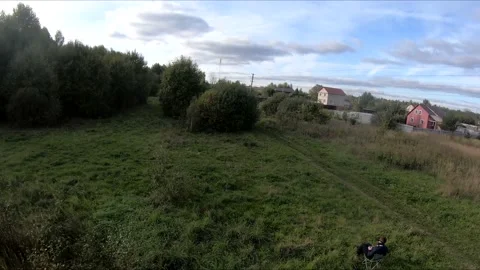 Flying on an fpv drone in a green field, against the background of a forest Stock Footage 166840918
