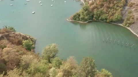 Flying with FPV racing drone down a tree covered hill and above a bay full Stock Footage 234253867