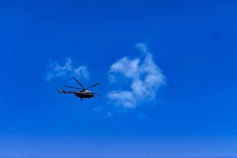 Flying helicopter on the background of clouds and blue sky Stock Photos