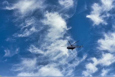 Flying helicopter on the background of clouds and blue sky Stock Photos