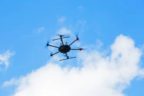 Flying hexacopter drone Flying hexacopter drone against a blue sky with cl... Stock Photos