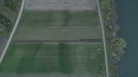 Flying high above a tractor plowing the big green field near river Mur, 4K Stock Footage 74311232
