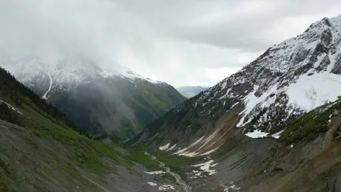 Flying high in the mountains, falling snow in a mountain gorge, aerial view Stock Footage 277005920
