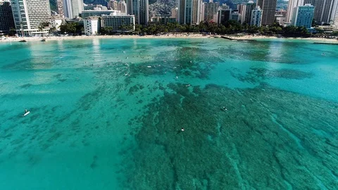 Flying high over the clear blue water and surfers outside Waikiki beach, Video stock 109454980