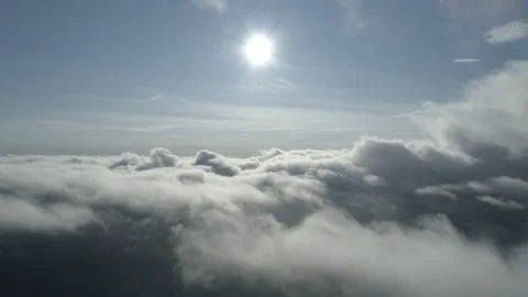 Flying high over the clouds into the beautiful blue sky with bright sun Stock Footage 147901011