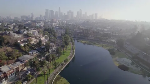 Flying high over Echo Park Lake with Downtown Los Angeles in the background  Stock Footage 233937849