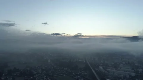 Flying high over a misty small town revealing a cloudy Austria landscape Stock Footage 147926465