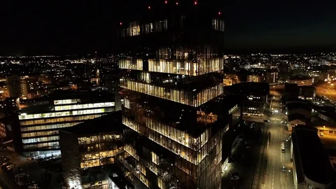 Flying up a highrise with reflecting windows with a view of a city at night Stock Footage 87014203