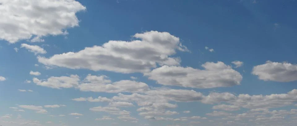 Flying, light, spring clouds against the blue sky. Stock Photos