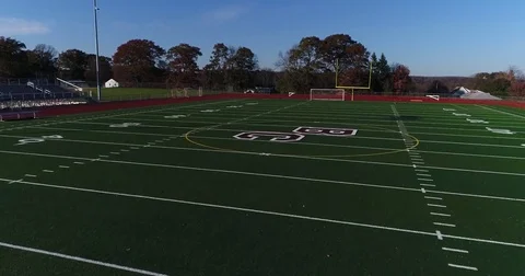 Flying low above high school football field then rising up above trees Stock Footage 82327040