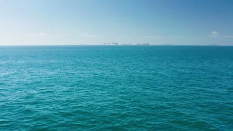 Flying low, above the open-ocean's surface towards container ships off HB coast Stock Footage 282256078
