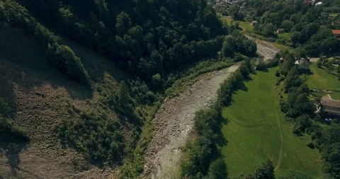 Flying low above the river carving its way through the spring valley. 4k Stock Footage 109795881