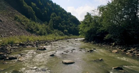 Flying low above the river carving its way through the spring valley. 4k Stock Footage 109796348