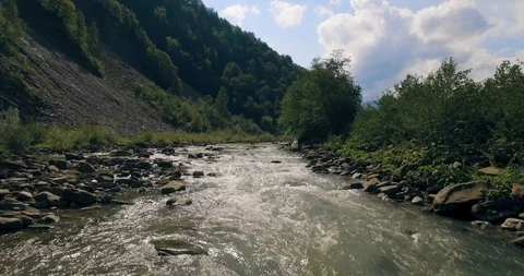 Flying low above the river carving its way through the spring valley. 4k Stock Footage 109796881