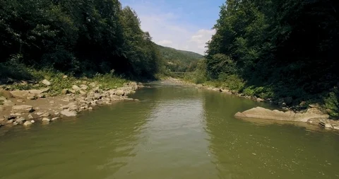 Flying low above the river carving its way through the spring valley. 4k Stock Footage 109798050