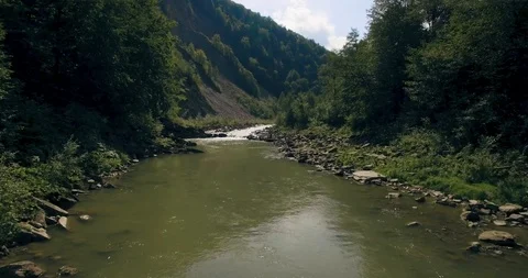 Flying low above the river carving its way through the spring valley. 4k Stock Footage 109801220