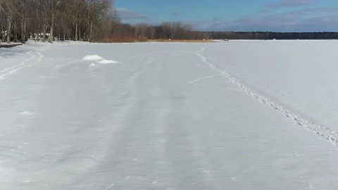 Flying low above the snow, with a drone, flying towards high grass in winter 動画素材 164382013
