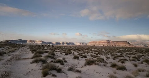 Flying low across a snow-dusted desert landscape, rising toward cliffs Stock Footage 106483081