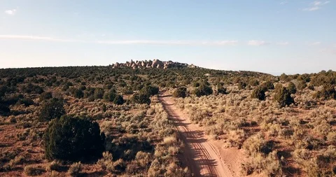 Flying low and fast over a dirt jeep track mountain biking trail in the desert Stock Footage 120057411