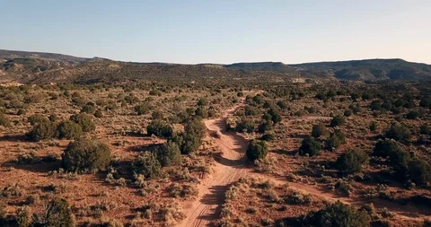 Flying low and fast over a dirt jeep track mountain bike trail in the desert Stock Footage 120062332