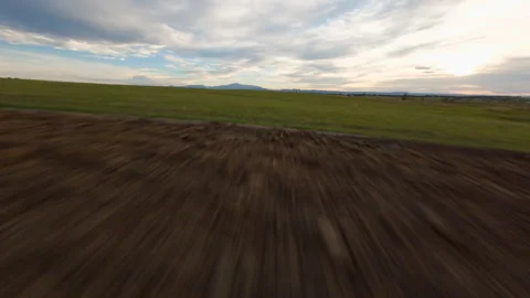 Flying Low and Fast Over Road and Green Grass with Mountain Peak in the Dist Stock Footage 316104186